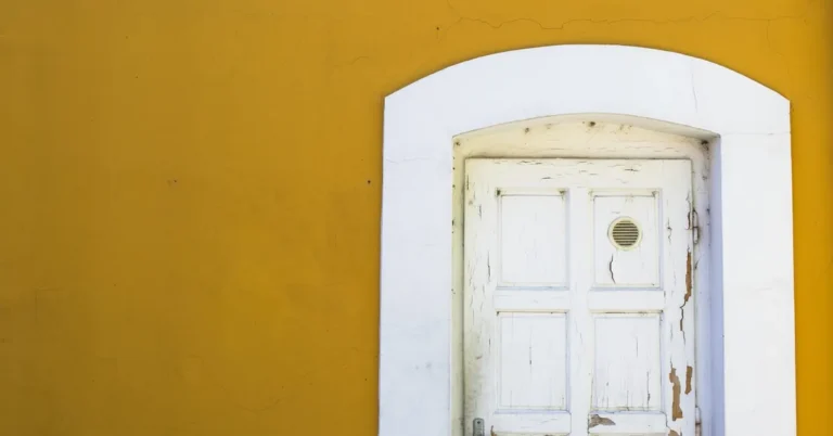 Weathered wooden door with chipped white paint set in a white frame