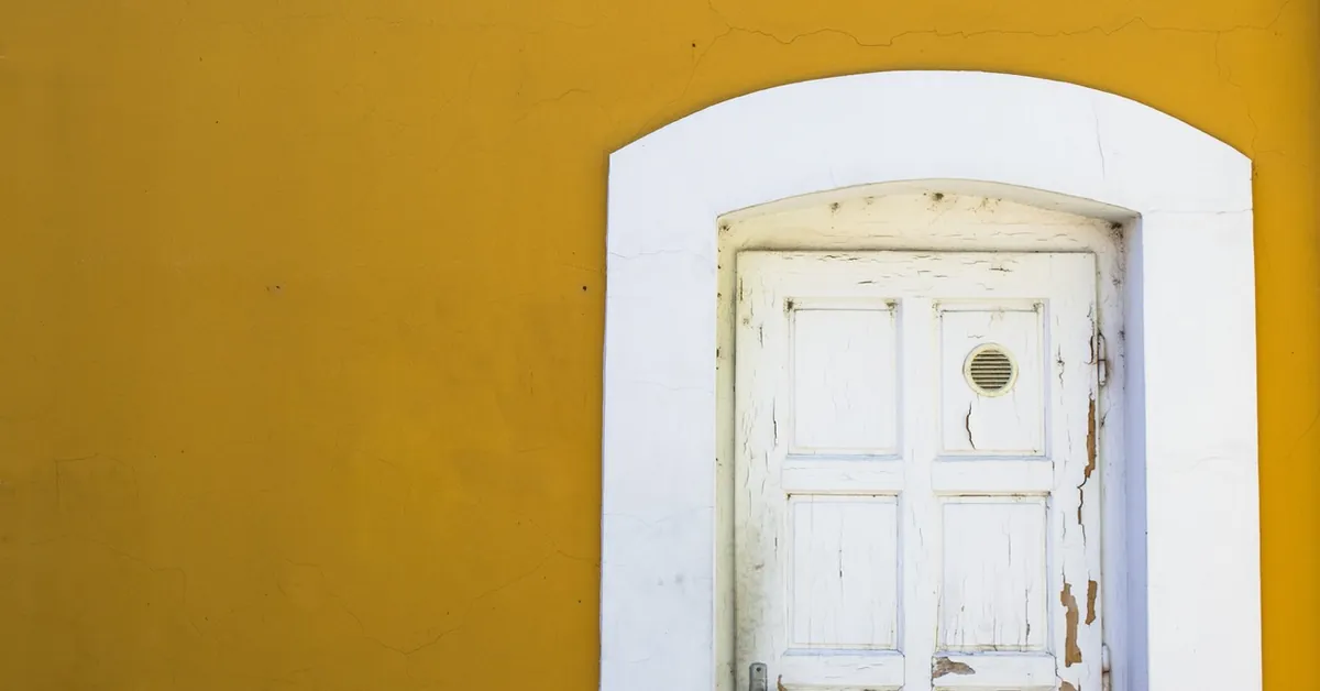 Weathered wooden door with chipped white paint set in a white frame