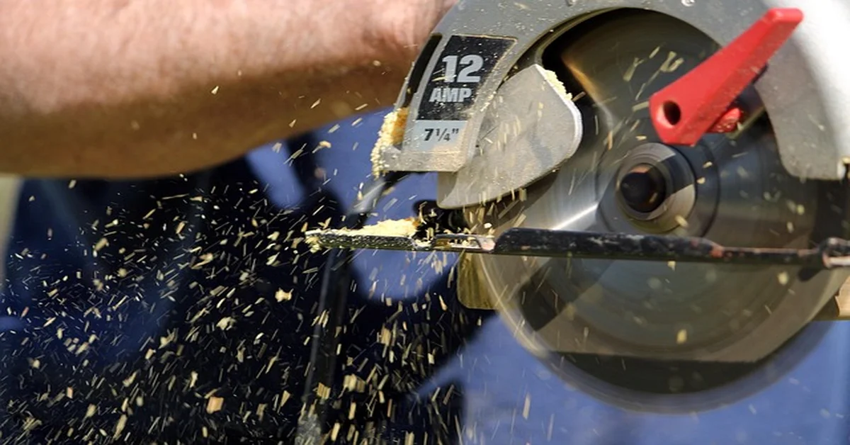 Circular saw blade cutting through wood with sawdust flying