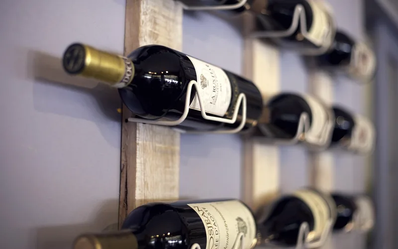 Close-up of a wall-mounted wooden wine rack holding bottles Close-up of a wall-mounted wooden wine rack holding bottles