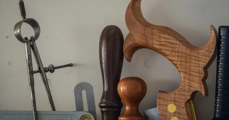 Hand tools on a shelf including a handsaw with a curved wooden handle