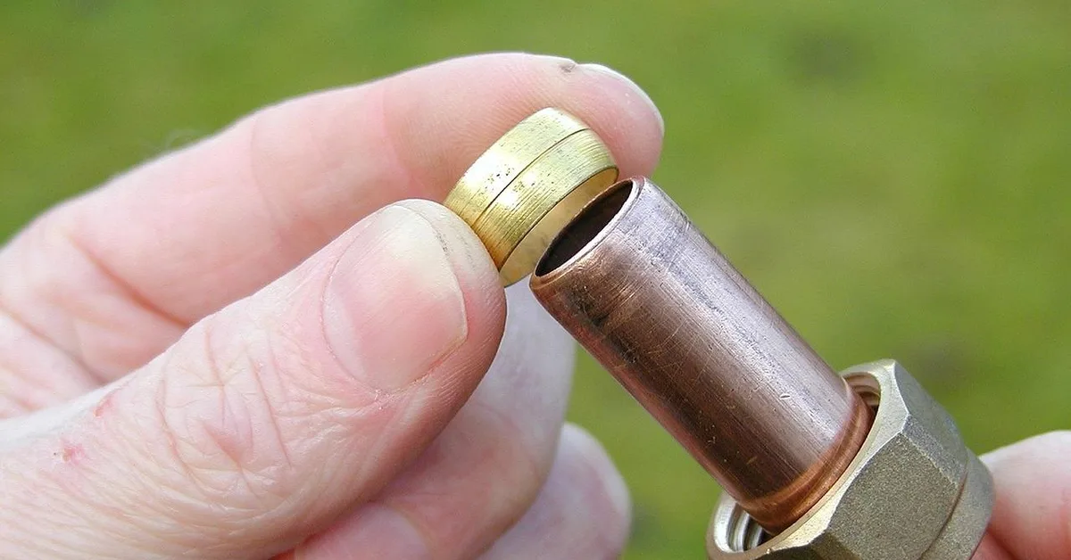 Copper pipe segment cut clean with a metal-cutting blade, fitted with a brass compression fitting