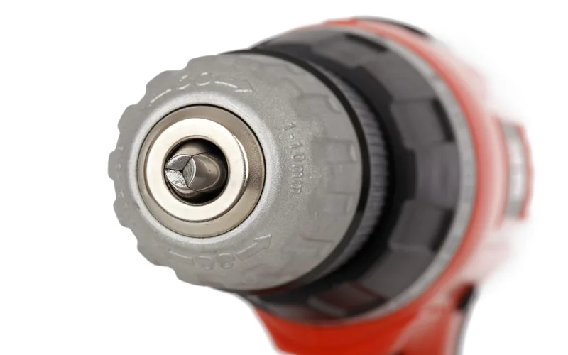 Close-up of a cordless drill chuck and clutch settings on a red and black power tool