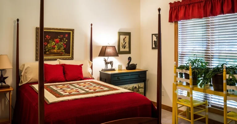 dark mahogany four-poster bed frame with cream walls and deep red bedding