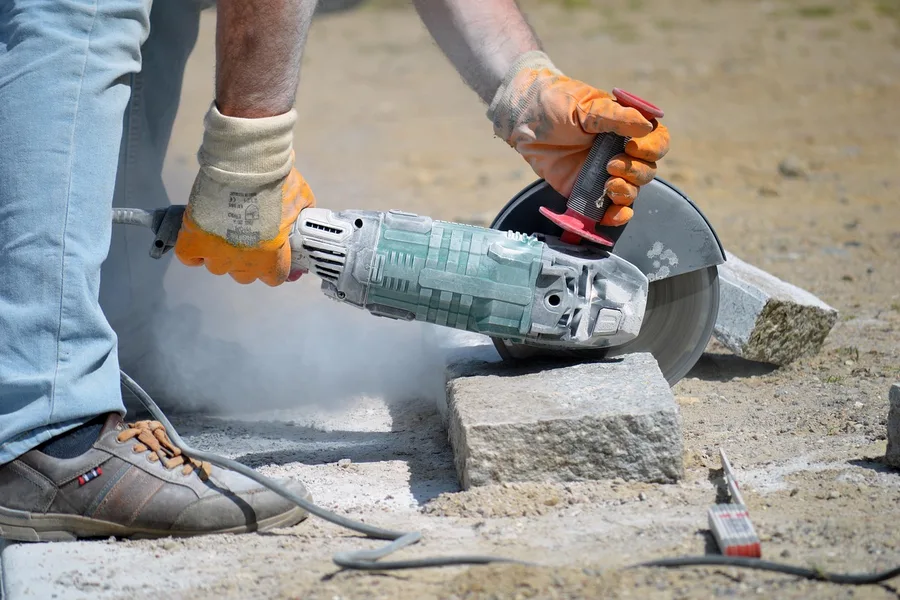 Diamond blade dry-cutting a granite paver, dust cloud visible with no water feed Diamond blade dry-cutting a granite paver, dust cloud visible with no water feed