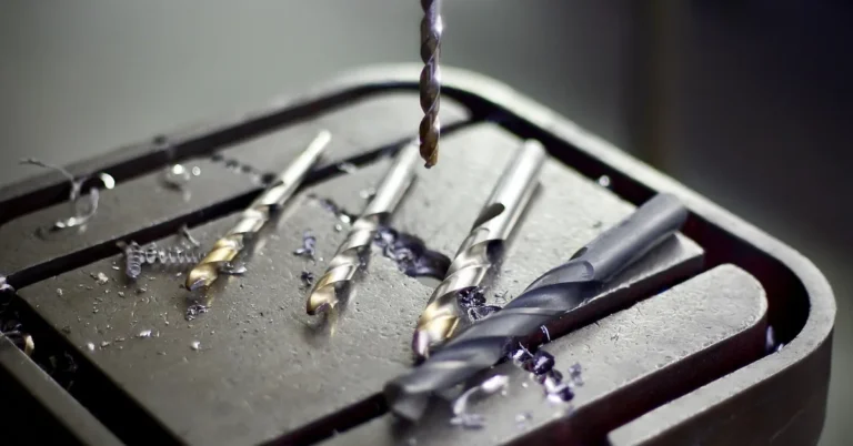 drill press chuck with fresh drill bits and metal shavings on the table