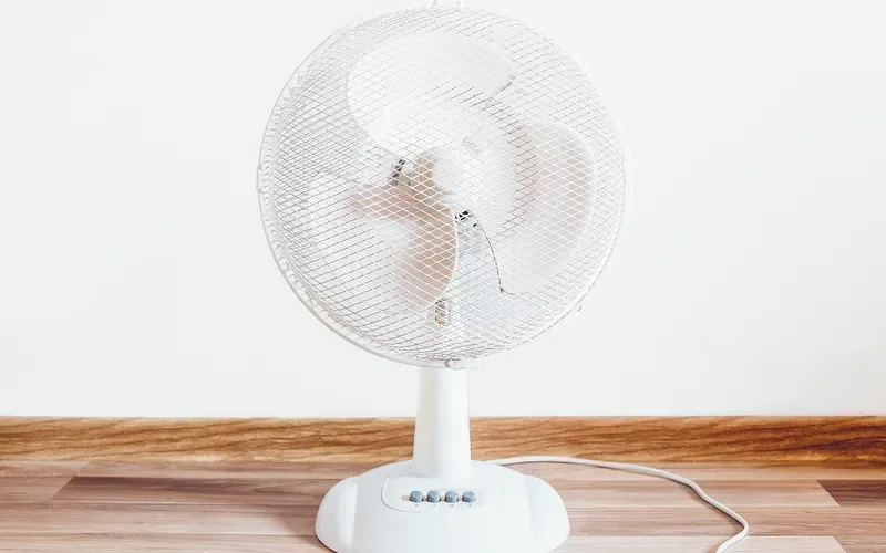 Electric fan on a wood floor to move air while a finish dries
