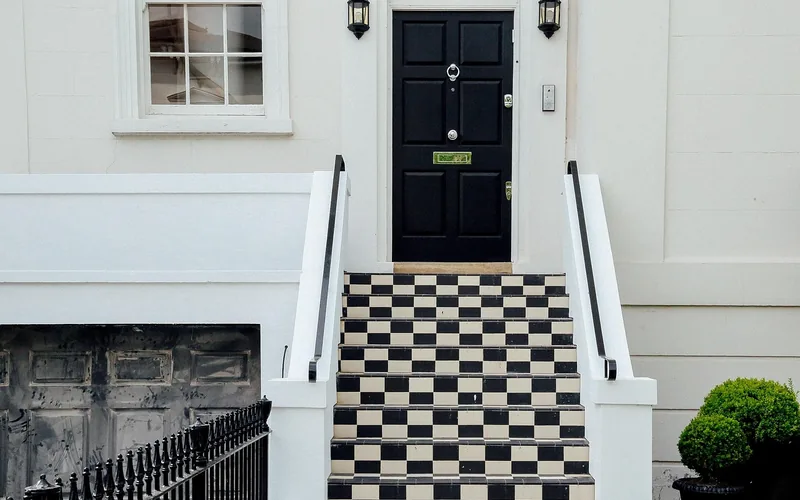 Black panel front entry door with checkered tile steps leading up to the entrance Black panel front entry door with checkered tile steps leading up to the entrance