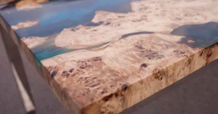 Close-up of a live-edge burl wood table corner finished with blue-tinted epoxy resin coating