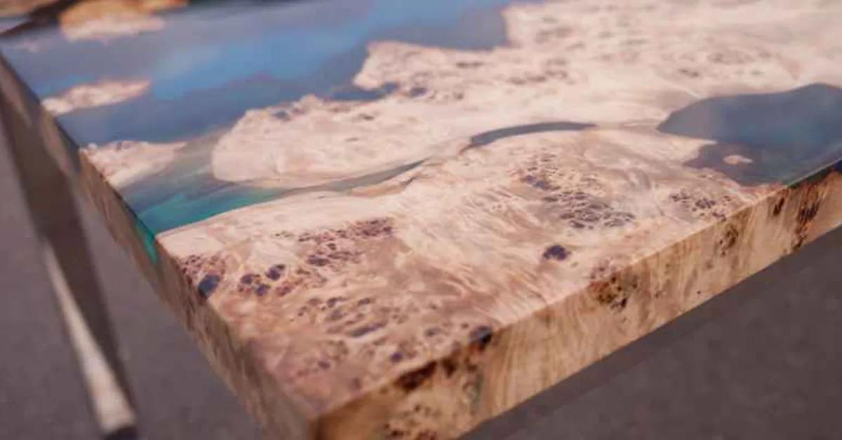 Close-up of a live-edge burl wood table corner finished with blue-tinted epoxy resin coating