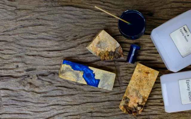Two-part food-safe epoxy resin Part A and Part B being measured and mixed on a wood workbench