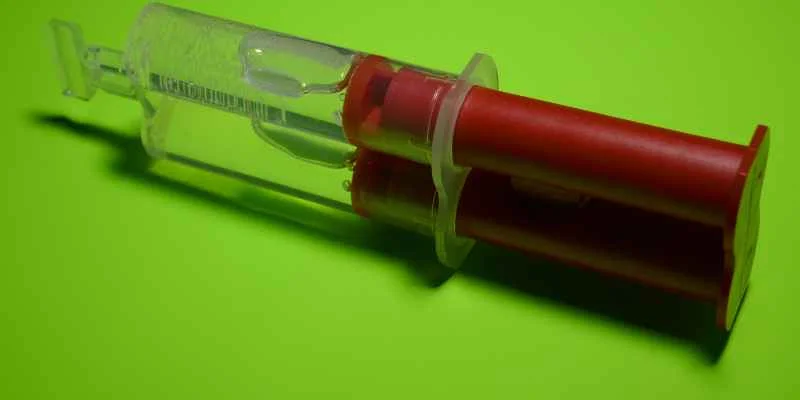 close-up of a red-plunger glue syringe filled with clear adhesive