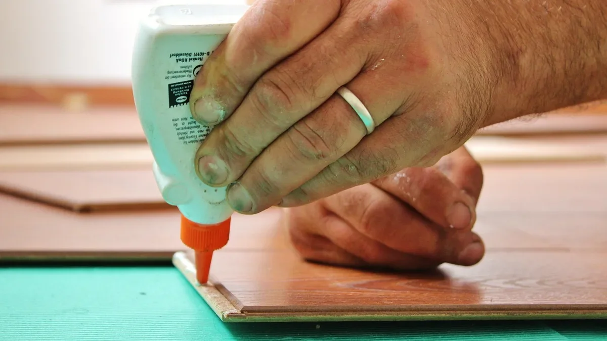 Hand applying glue along the edge of a wood board during a glue-up