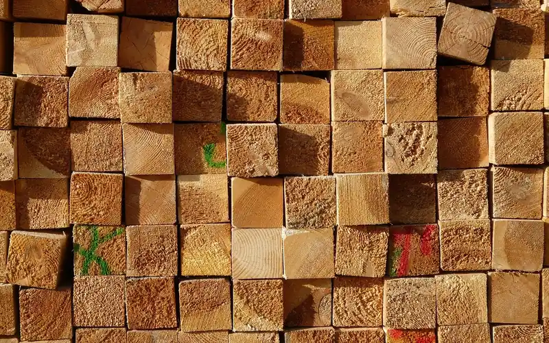 Stacked square lumber posts with grading marks at a sawmill