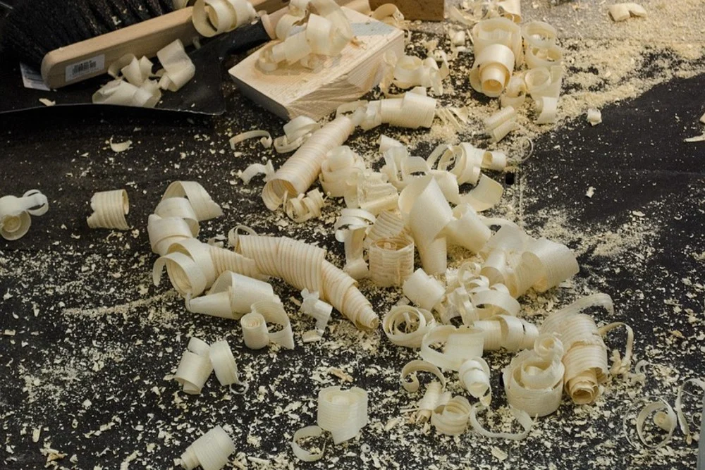Curled hand plane shavings scattered on a workshop floor