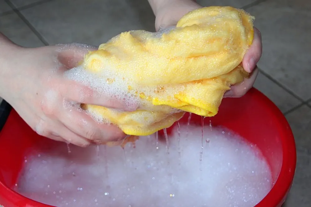 Hands wringing water out of a cloth over a bucket Hands wringing water out of a cloth over a bucket
