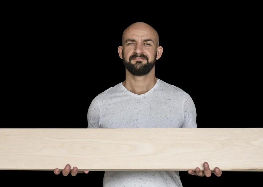 A craftsman holding a pale wood board
