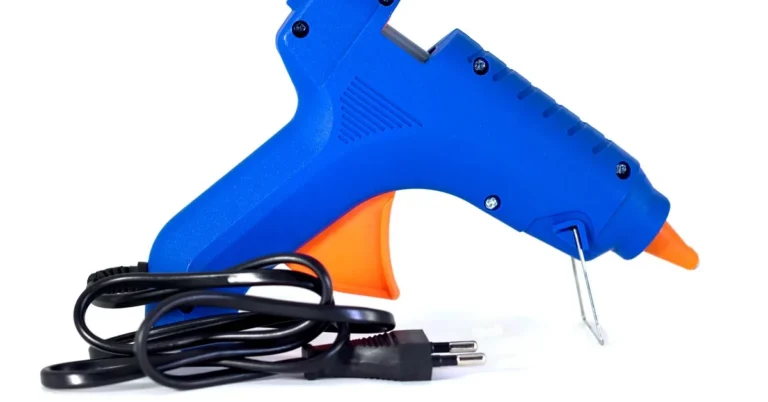 Blue hot glue gun with orange nozzle and cord, unplugged on white background