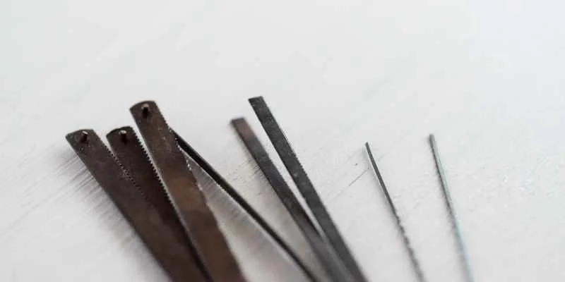 Jeweler's saw blades of varying widths and tooth counts laid out for comparison