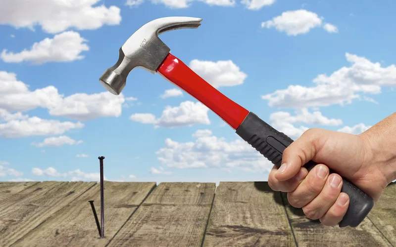 carpenter using hammer and nails during outdoor wood deck framing construction
