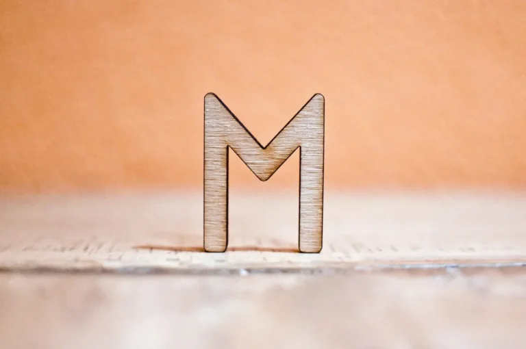 A laser-cut plywood letter standing on a wooden surface