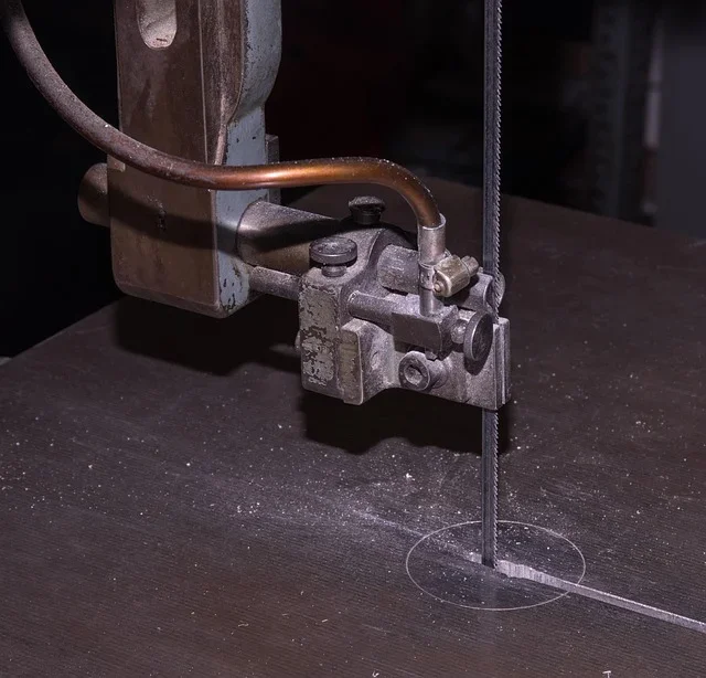 Close-up of a band saw blade running through the upper blade guide assembly