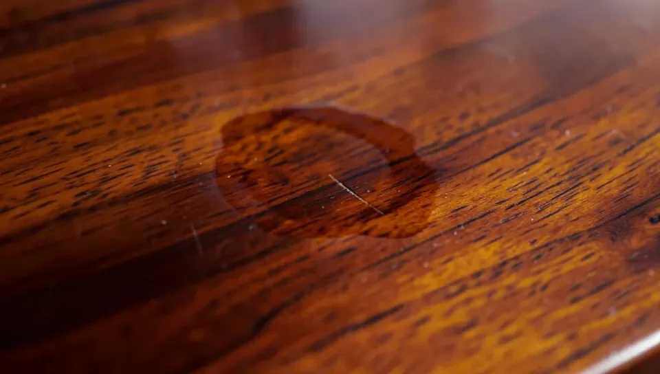 Mahogany table surface showing a scratch and water ring