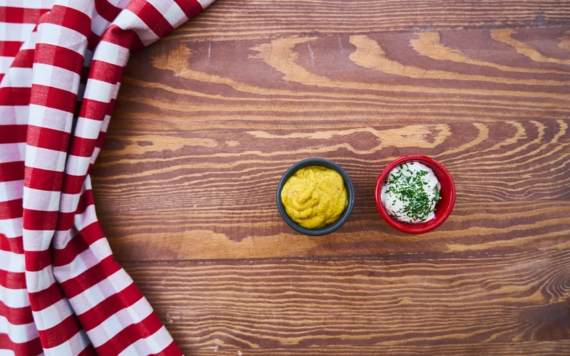 mayonnaise in a small bowl on a wood table small bowl of mayonnaise beside mustard on a wood table, the kitchen staple used in the water-ring folk remedy