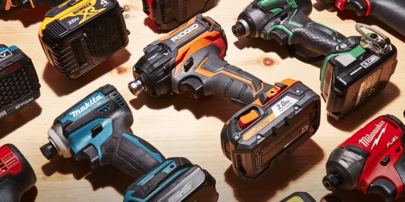 Multiple brands of cordless power tools and batteries laid out for comparison