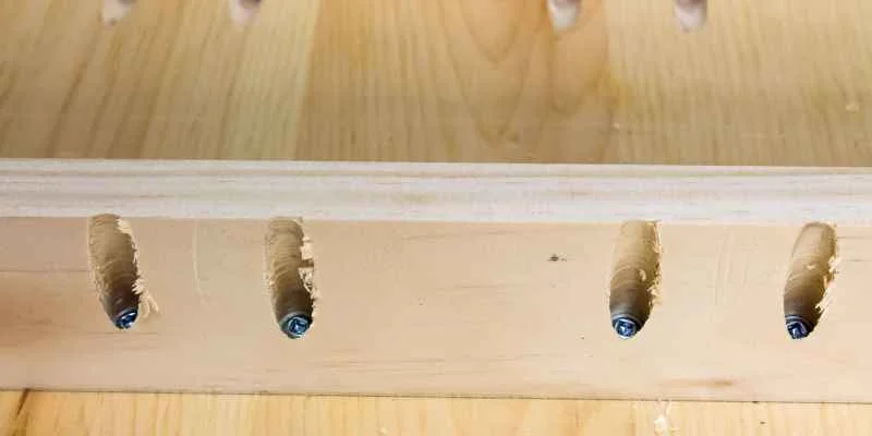 Four pocket holes drilled along a board edge, evenly spaced for a face-frame joint