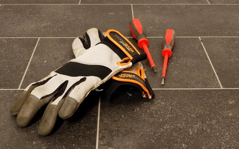 protective work gloves and screwdrivers on a workshop floor