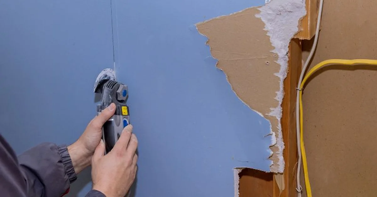Oscillating multi-tool cutting into drywall for a repair