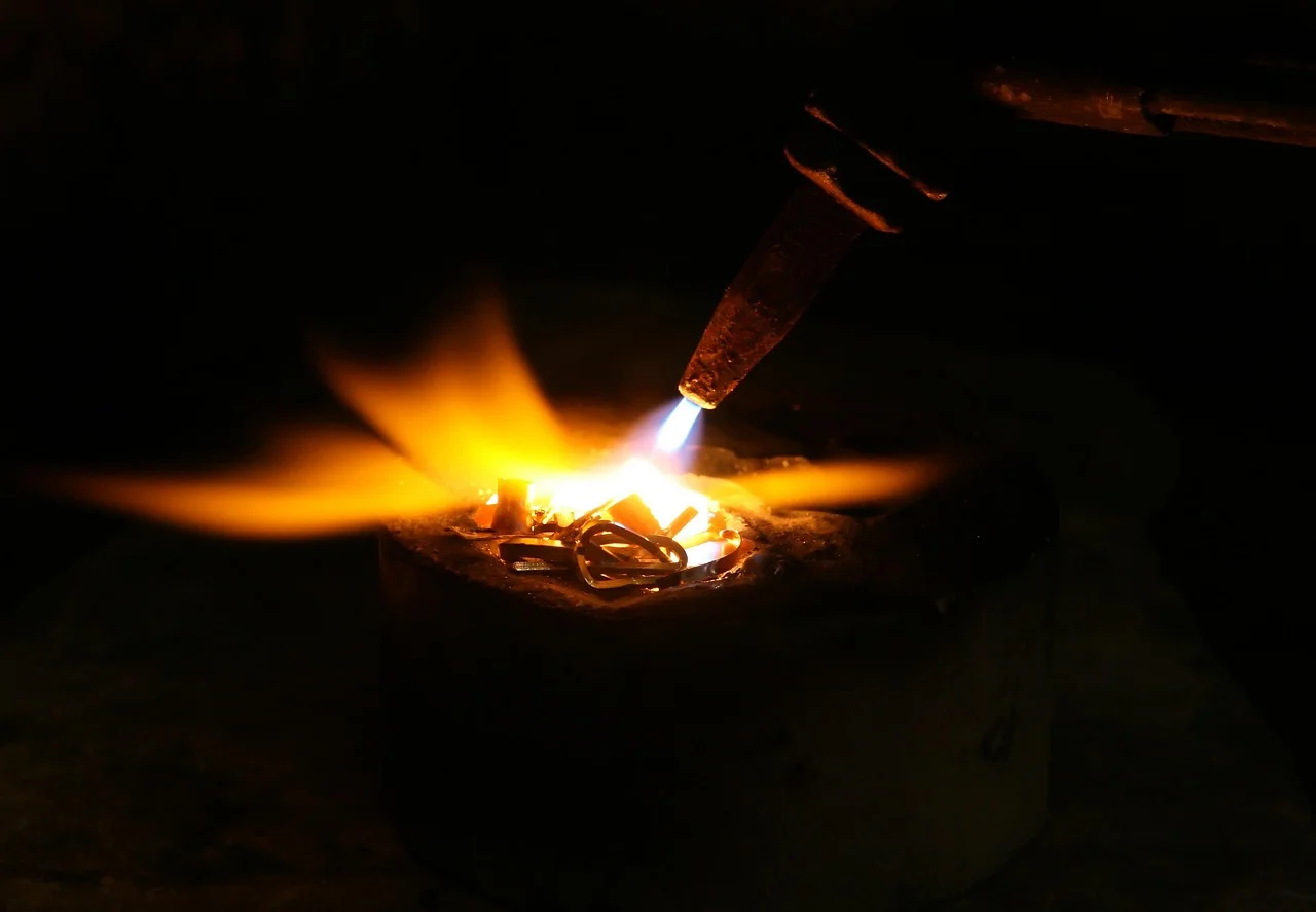 Close-up of an oxy-fuel torch flame melting metal, showing the concentrated high-temperature flame produced by mixing oxygen and acetylene