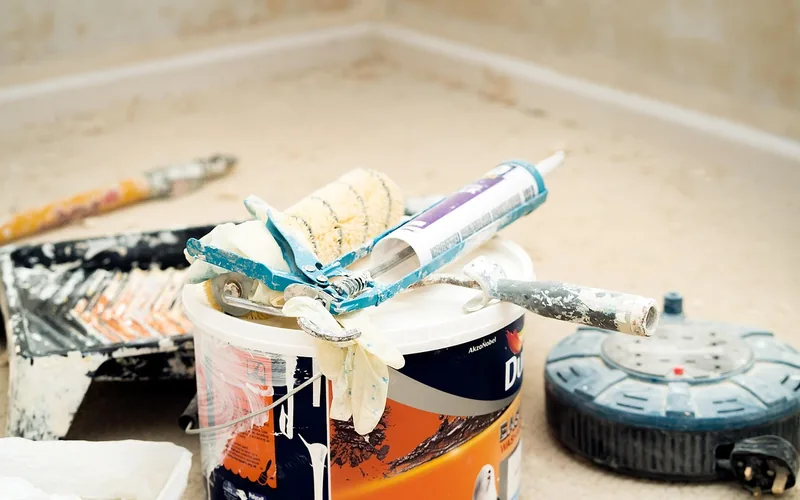 paint bucket with a roller and caulking gun resting on top after a home renovation job paint bucket with a roller and caulking gun resting on top after a home renovation job