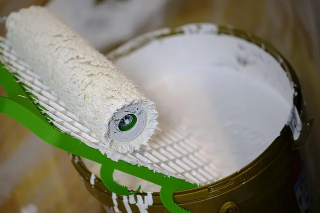 Paint roller with white nap fibers against paint bucket