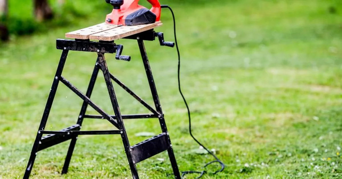 Folding portable workbench holding a circular saw with a plywood board, outdoor DIY cutting station