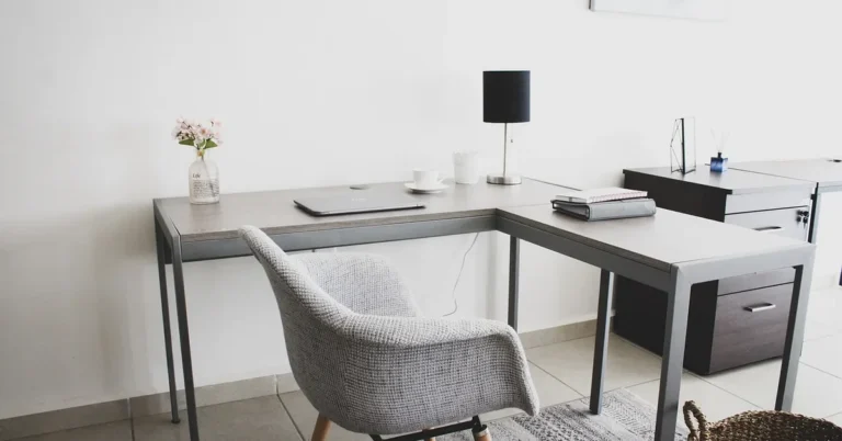 L-shaped desk with metal legs and a gray fabric chair in a bright home office