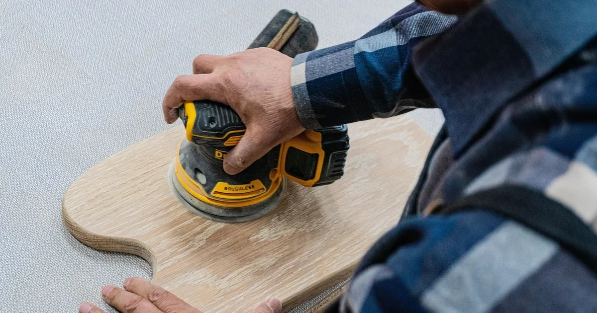 Random orbit sander sanding an oak board with hook and loop sandpaper