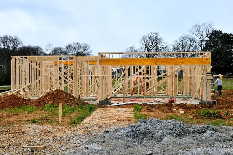Wood-framed house under construction with roof trusses ready for plywood sheathing installation Wood-framed house under construction with roof trusses ready for plywood sheathing installation
