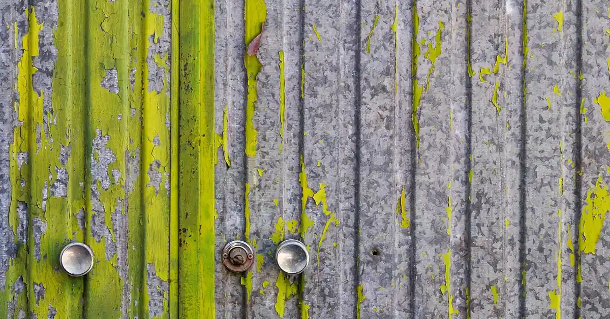 Peeling paint on an old corrugated metal door before repainting