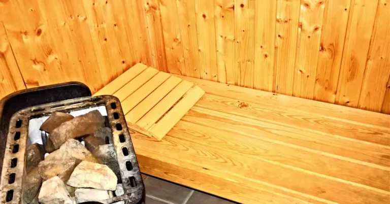Sauna interior with a wood bench, paneled walls and a rock-filled heater