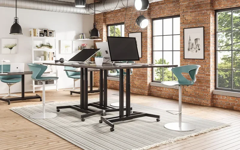 Height-adjustable sit-stand desks in an open office with a brick wall Height-adjustable sit-stand desks in an open office with a brick wall