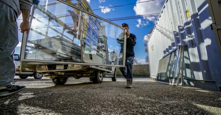 Two installers carrying a glass door frame from a truck