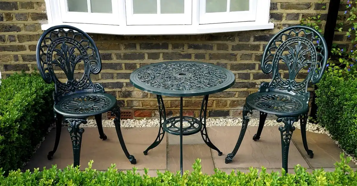 stone paving tile patio with bistro table and chairs against a brick house wall