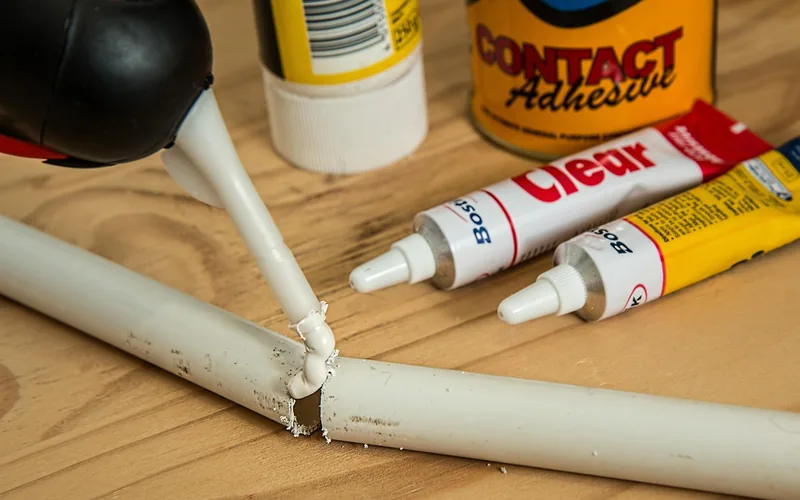 person applying super glue adhesive to repair a broken household item pipe
