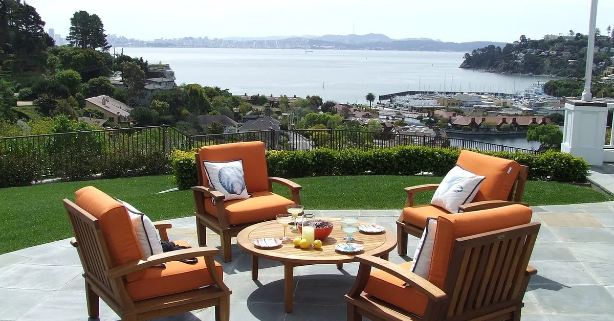 Teak patio chairs and round coffee table on a stone terrace
