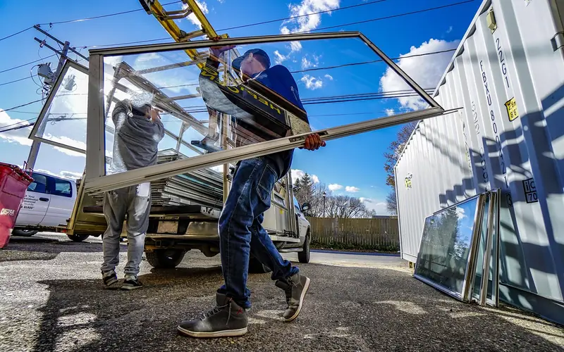 Two workers carrying a large glazed door frame