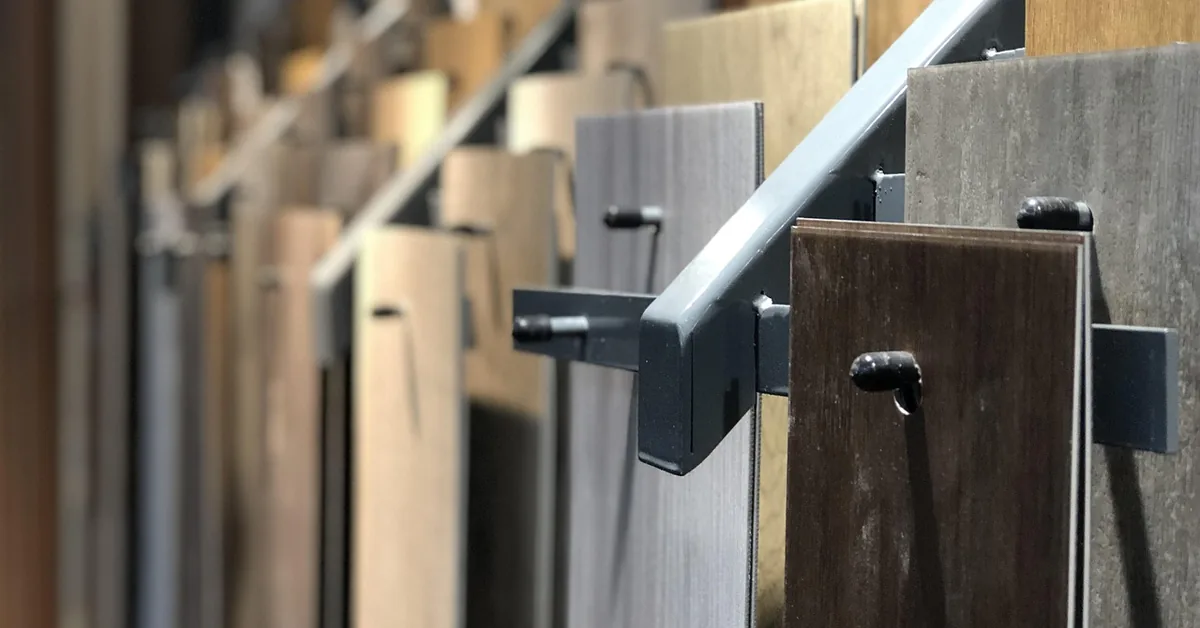 Rows of laminate and vinyl plank flooring samples displayed on a showroom rack