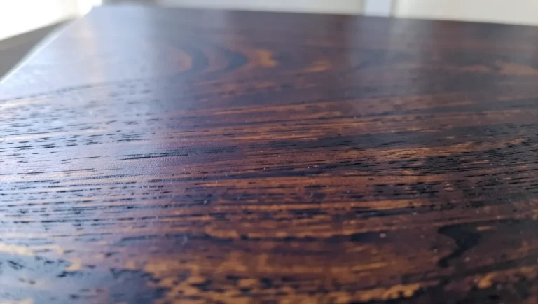Close-up of polished walnut wood grain showing its rich dark brown color and subtle purple undertone