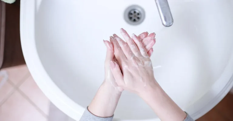 washing hands with soap and warm water at a bathroom sink to remove wood stain